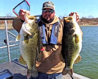 Bucky Nail holding up an 8- and 9-pound bass caught in the Horse Pasture Lake in the spring of 2021. Both of these bass are 48 months old.