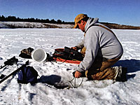 Figure 2. Graduate student Andy Jansen lowers a dissolved oxygen probe into the pond. He took readings just under the ice, at a middle depth, and just above the pond bottom.